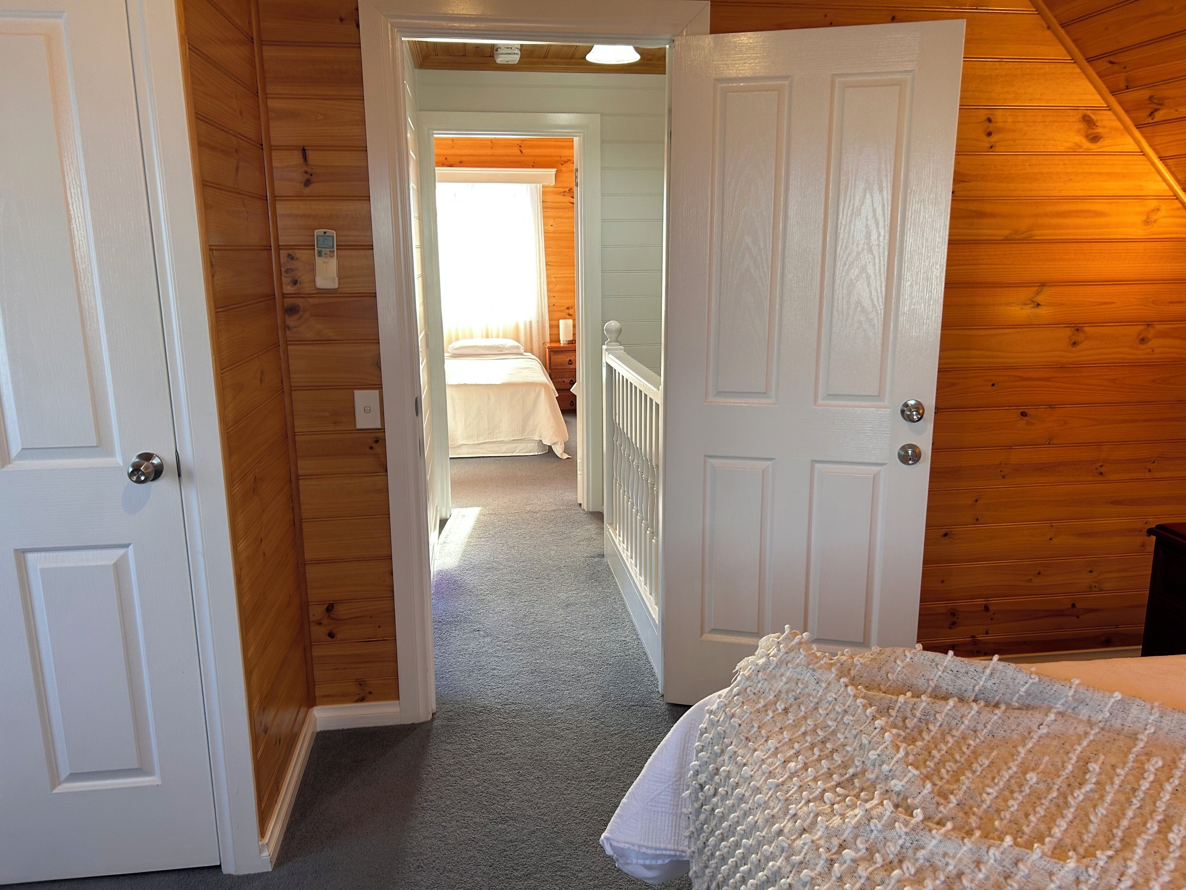 A wooden interior with a hallway leading to a bedroom.