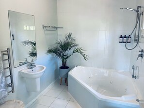 A modern bathroom with a bathtub, a sink, and a mirror. - Hideaway Studio Accommodation (Lindisfarne)