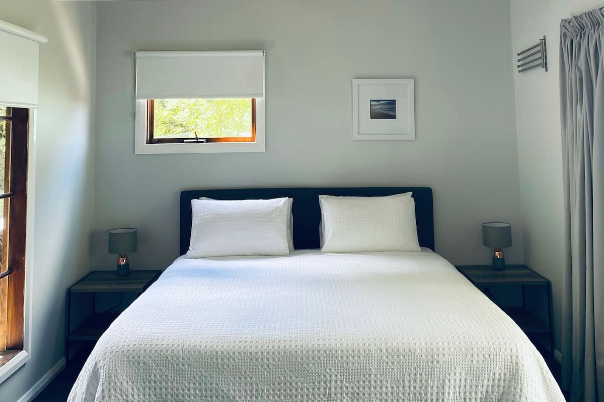 Une chambre à coucher comprenant un lit, deux tables de chevet, une fenêtre et un plafond orné d’un motif géométrique.