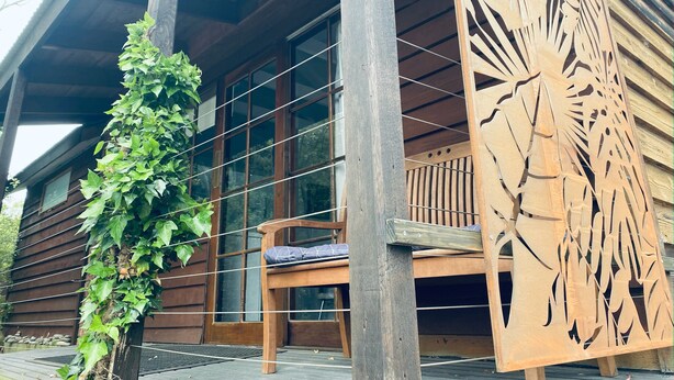 Una cabaña de madera con porche, banco y un panel decorativo de madera.