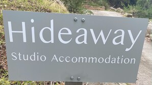 Señal para 'Hideaway Studio Accommodation' con un entorno natural y al aire libre de fondo.