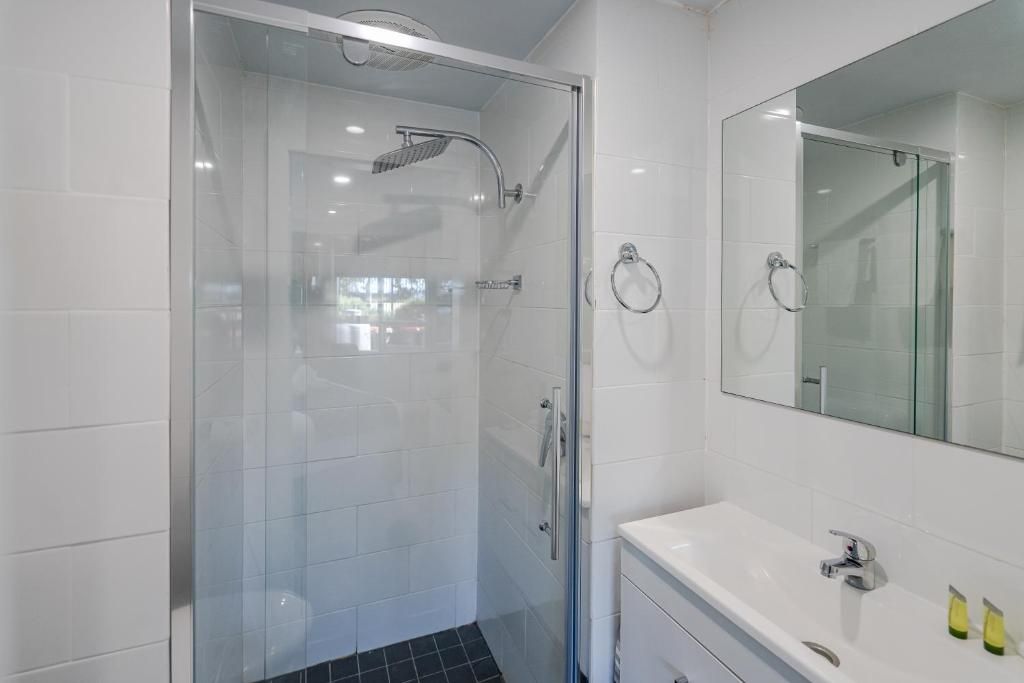 A modern bathroom with a glass-enclosed shower, a white sink, and a mirror above the sink.
