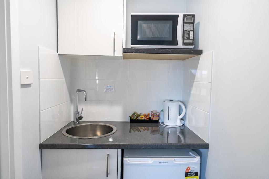 A compact kitchen with a stainless steel sink, a microwave, and a dishwasher.