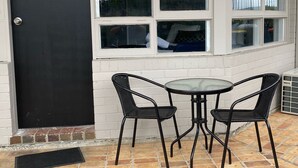 A black door with the number 26, a white brick wall, and a window with a view of a balcony and trees. - Bega Motel (Bega)