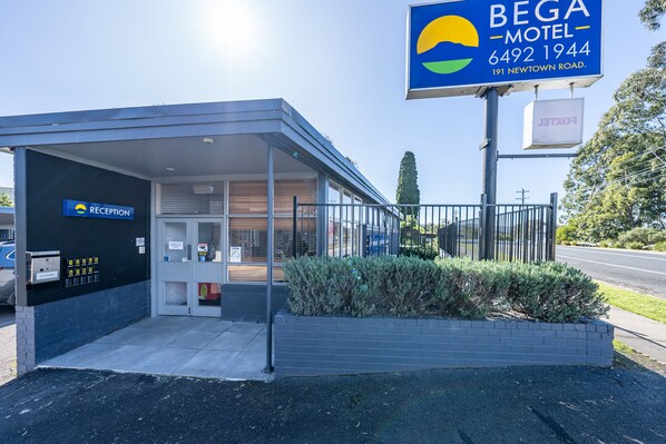 A motel with a reception area, a signboard, and a gated entrance.