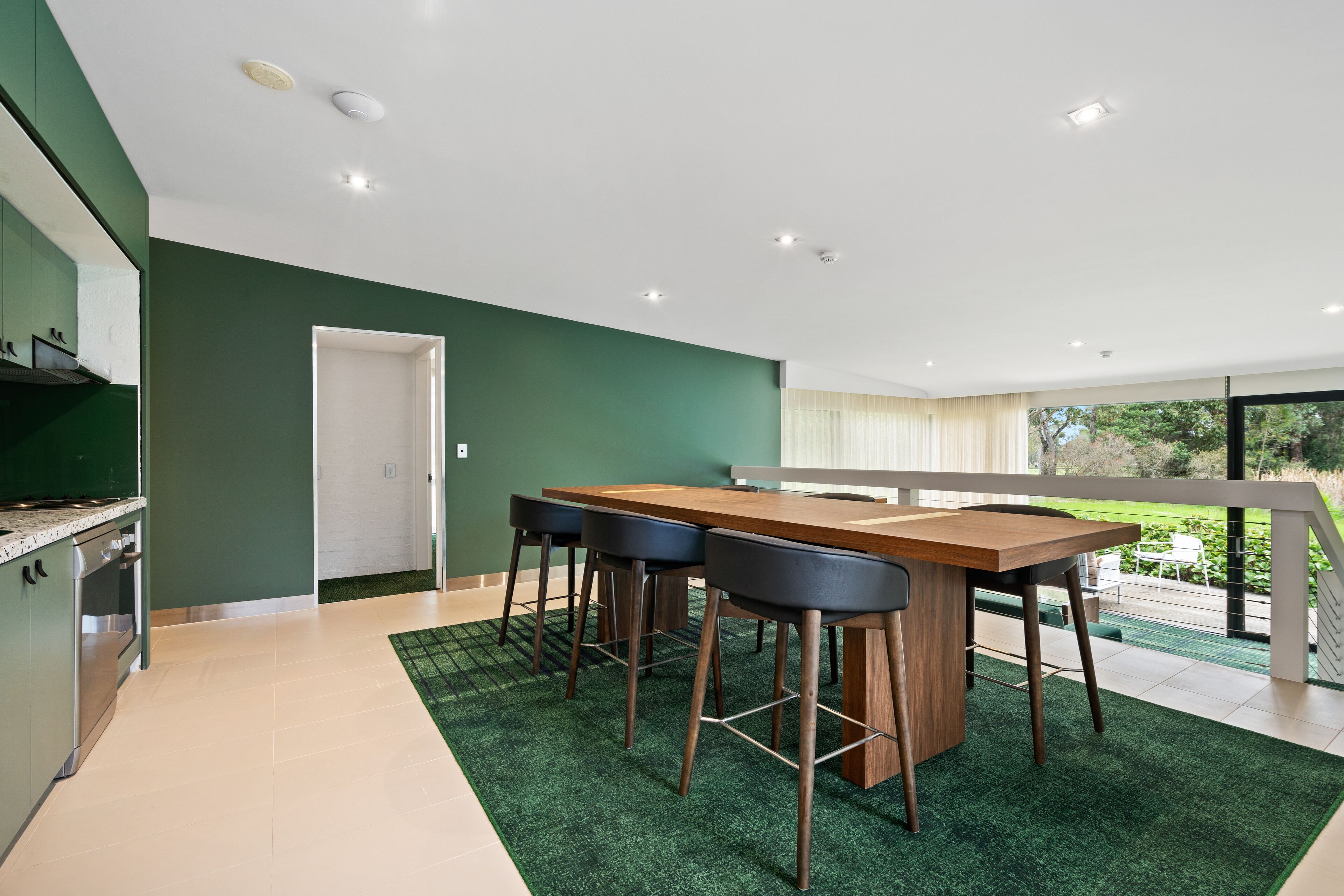 A modern kitchen with a dining area, a staircase, and a view of the outdoors.