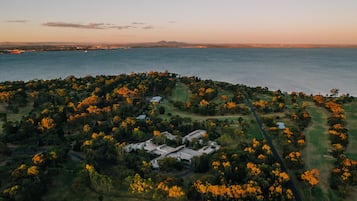 Residential homes surround a serene body of water, set amidst lush greenery and autumnal trees.