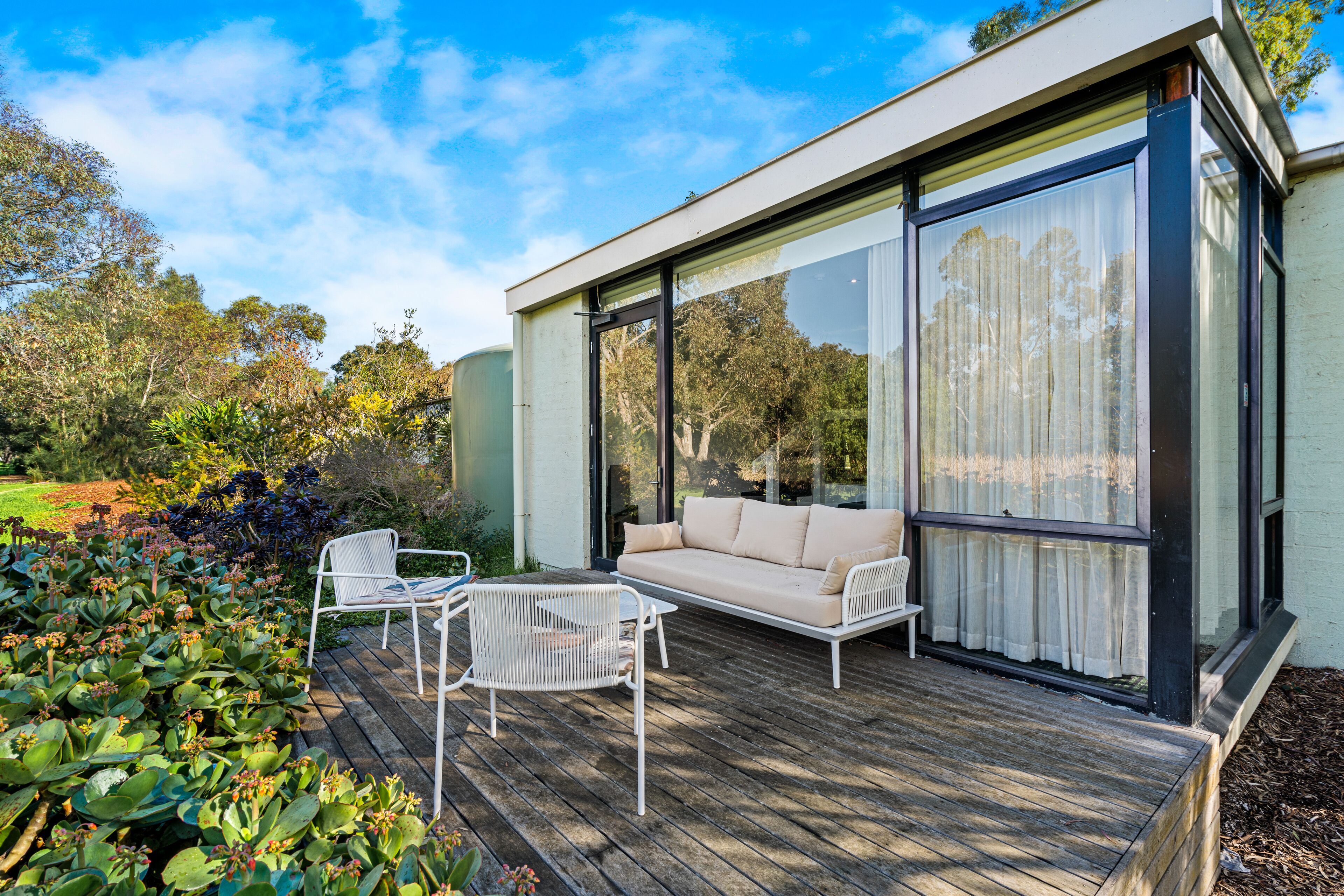 A modern house with a deck, a sofa, and a chair.