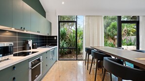 Una cocina moderna con un ventanal grande, un comedor con mesa y sillas, y vistas al jardín.