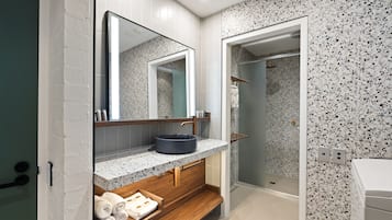 Un baño moderno con una bañera independiente, un espejo grande y una encimera de granito.