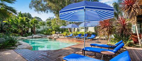 A poolside area with blue lounge chairs and striped umbrellas.