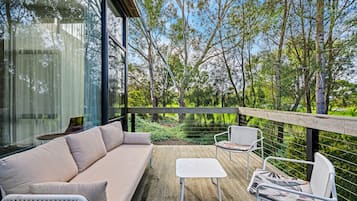 Relax on the deck with a comfortable sofa and chairs, surrounded by lush greenery and a scenic view.