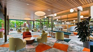 Un espacio interior moderno con suelo de estampado geométrico, muebles contemporáneos y amplios ventanales con vistas a zonas verdes.