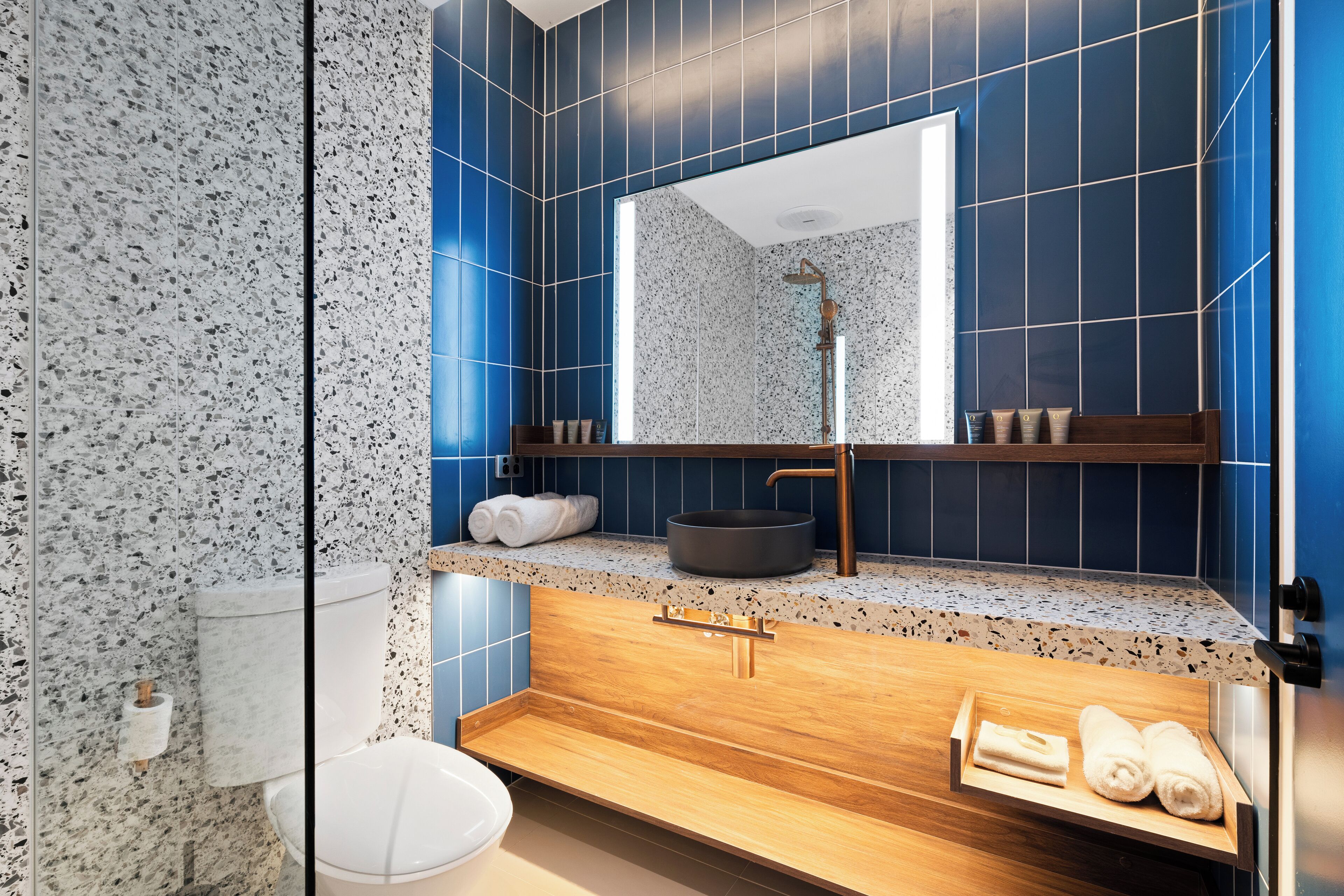 Un baño moderno con una bañera independiente, un espejo grande y un tocador de madera.