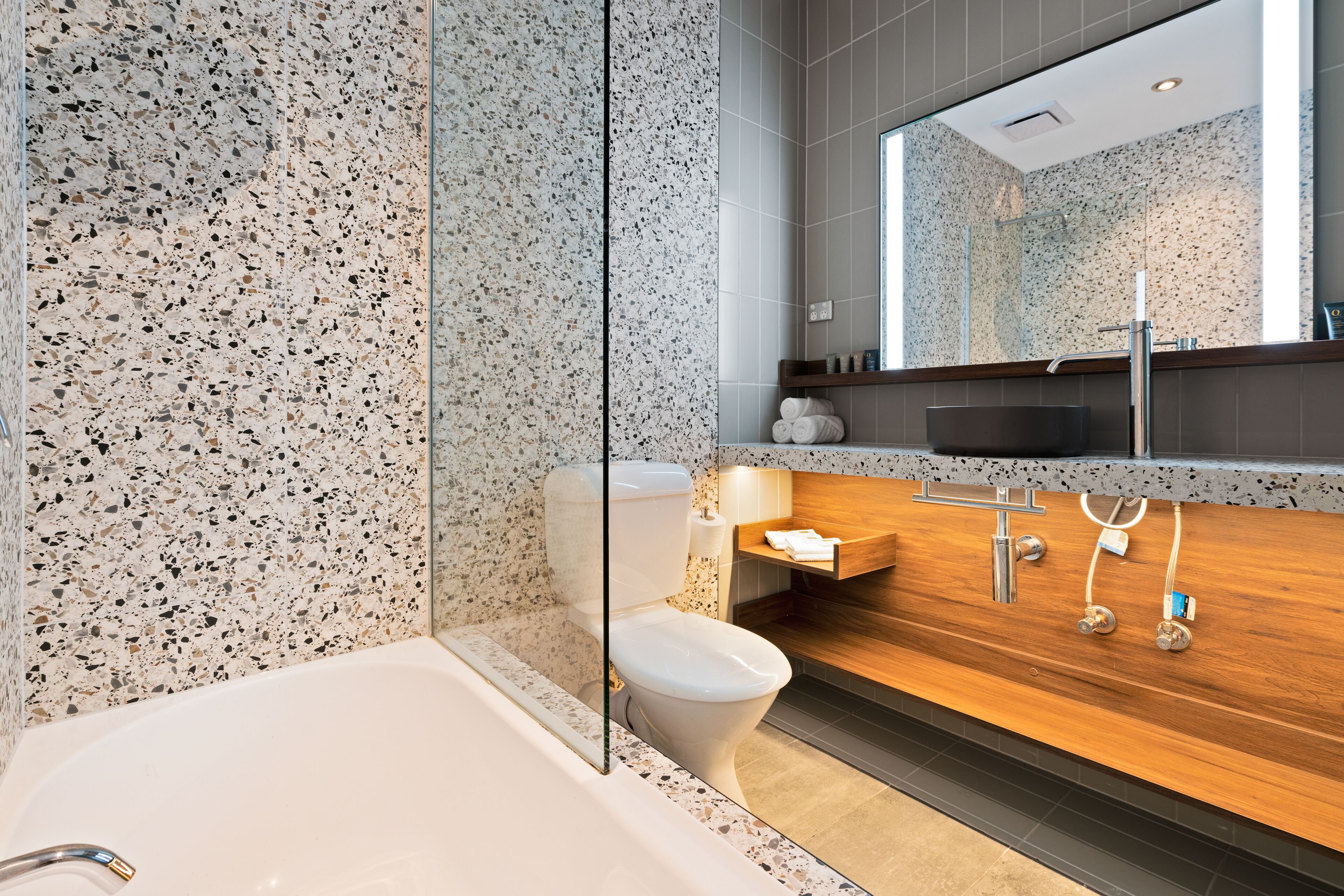 Un bagno moderno con una vasca freestanding, un water e un mobile lavabo con specchio.