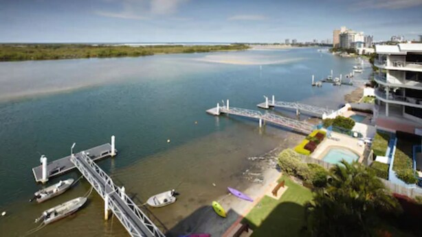 A marina with boats docked, a bridge, and buildings with balconies overlooking the water. - On The River Apartments (Maroochydore)