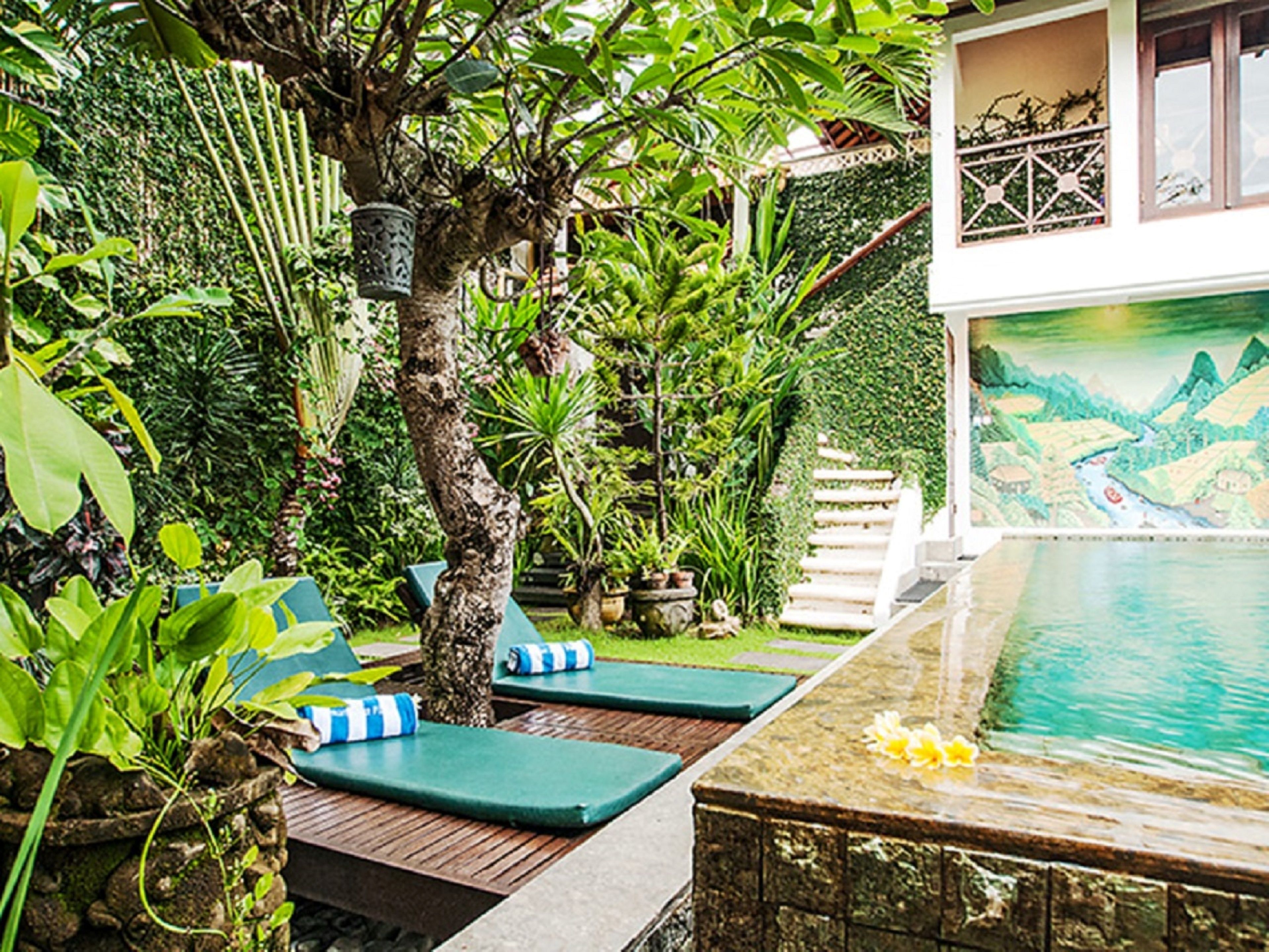 A pool area with lounge chairs and a mural of a landscape.
