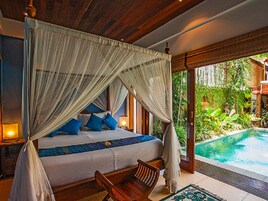 Camera da letto con un letto a baldacchino, una sedia di legno e vista su una piscina all'aperto.