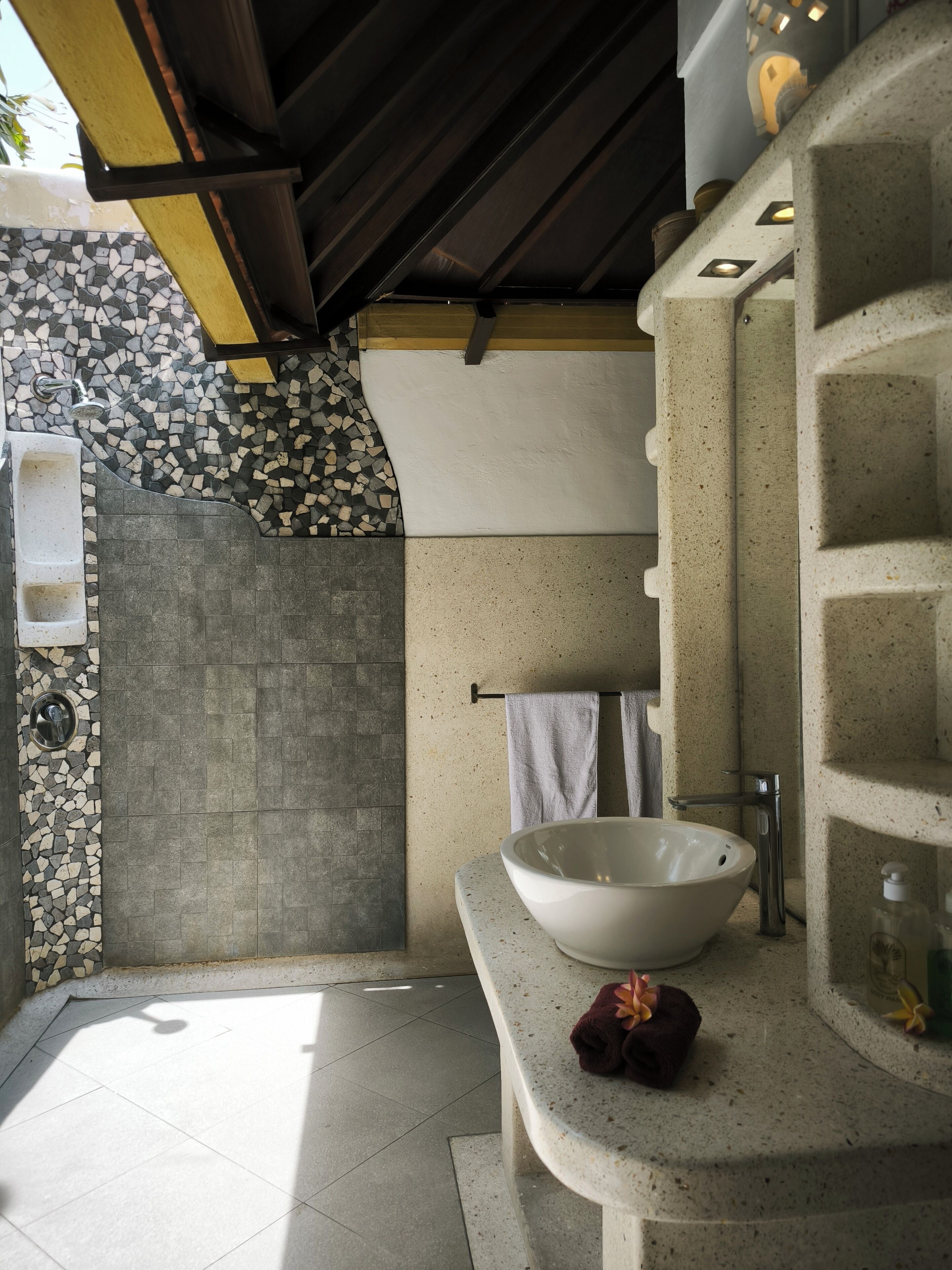 Une salle de bain moderne avec un grand lavabo sur pied, un espace douche et un sol carrelé.