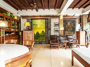 A spacious living room with wooden furniture, a large painting, and a stone fireplace.