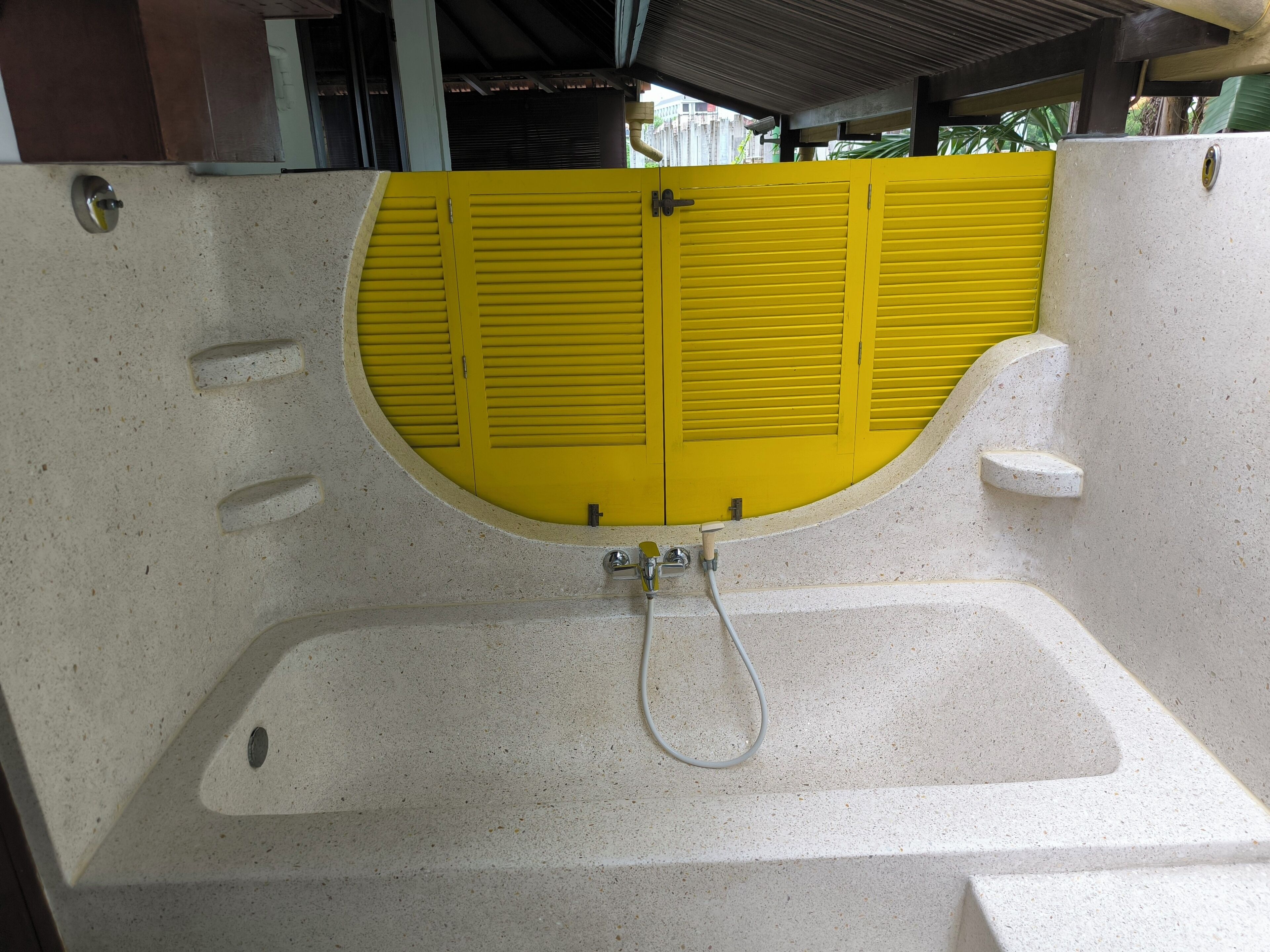 A bathtub with a yellow door and a showerhead.