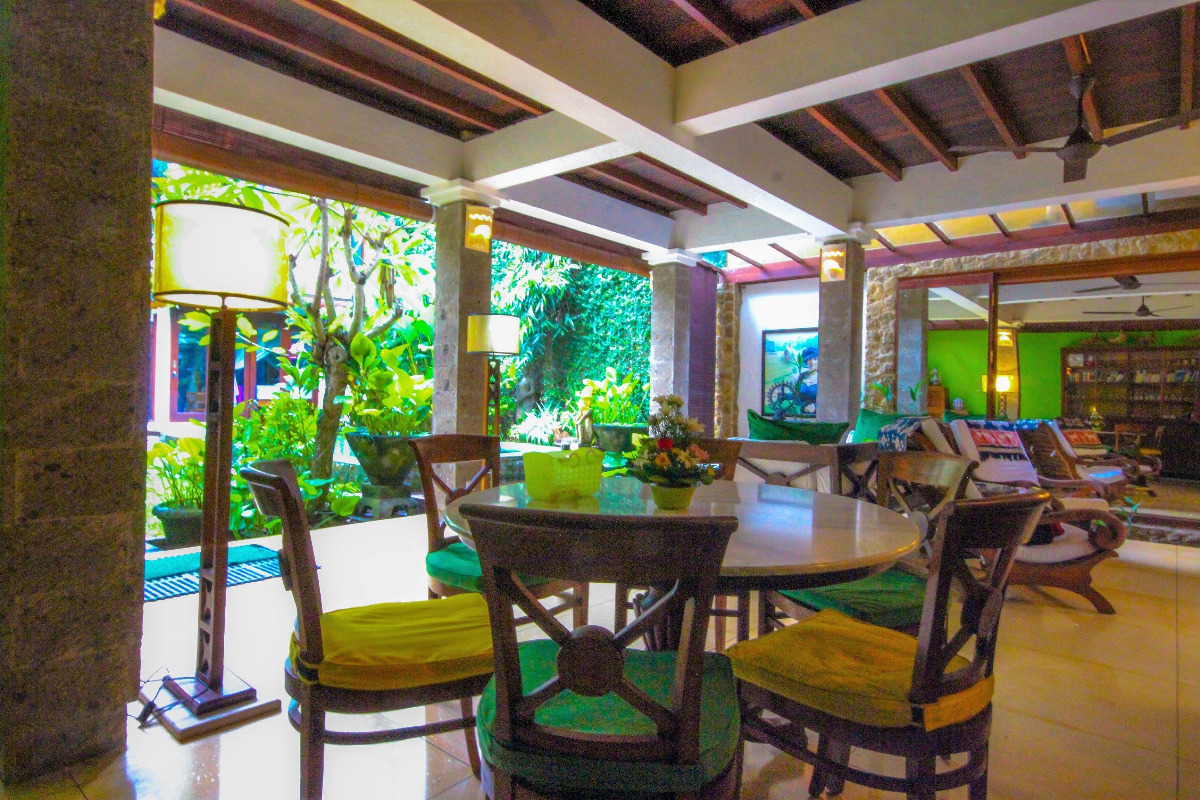 Restaurante com tema tropical, com mobiliário de madeira e vista para vegetação exuberante.