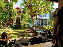 Un giardino tropicale con una statua in pietra, una panca di legno e una piccola fontana.