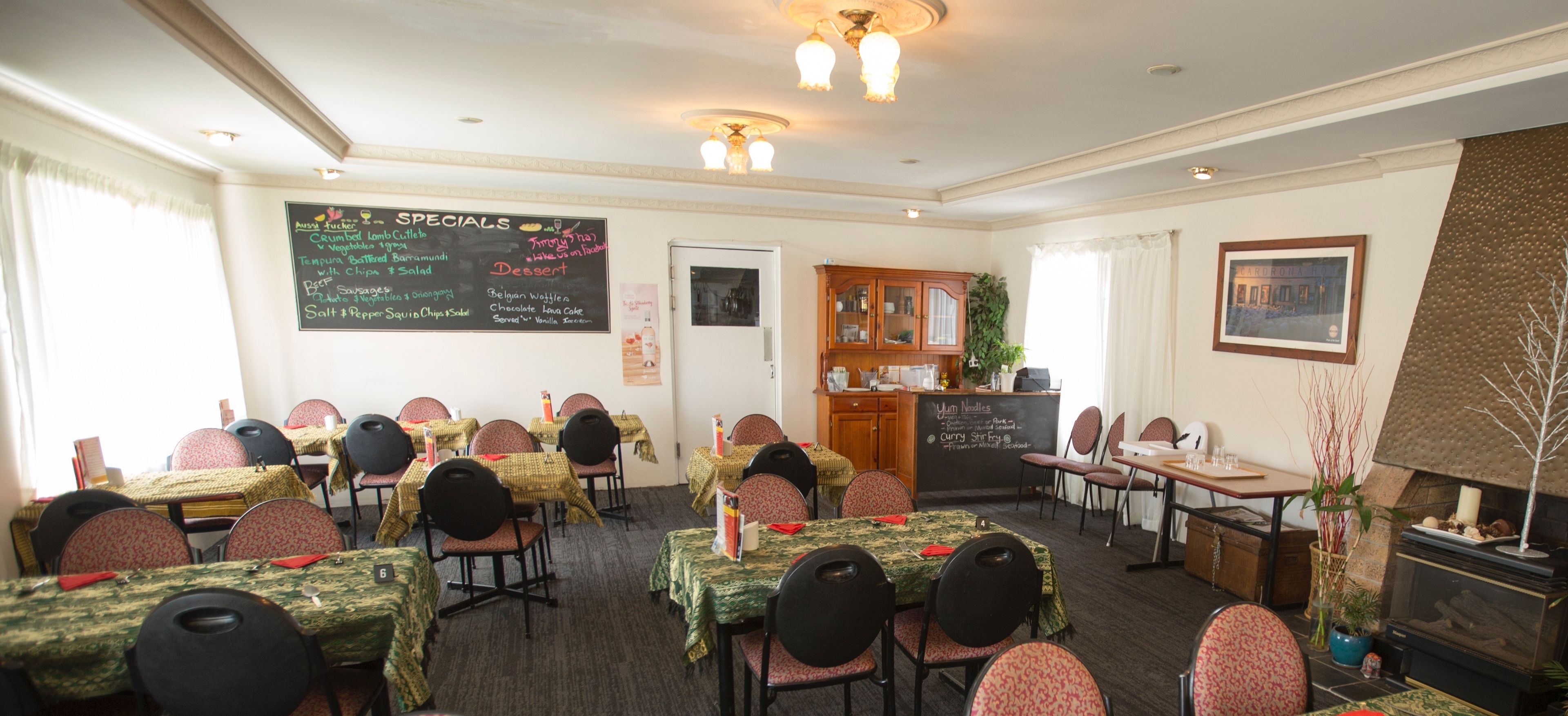 A dining area with tables set for service, a chalkboard menu, and a fireplace.