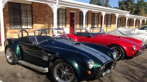 A row of vintage cars parked in front of a building with a brick facade and white columns. - Colonial Motor Lodge Scone (Scone)