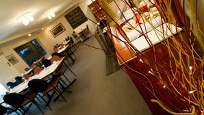 A dining area with tables and chairs, a kitchen area with appliances, and a decorative glass partition with red and yellow elements. - Colonial Motor Lodge Scone (Scone)