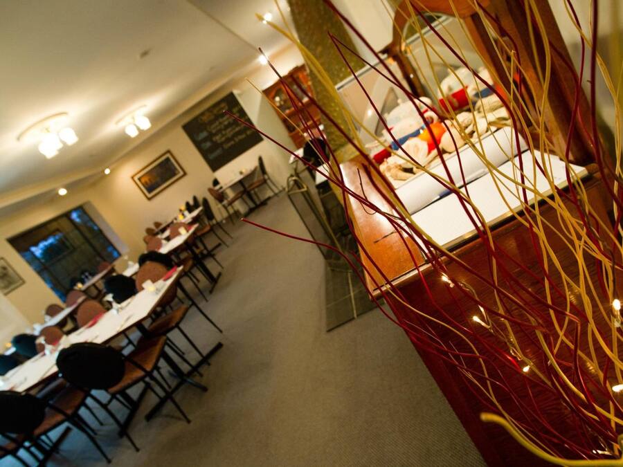 A dining area with tables and chairs, a kitchen area with appliances, and a decorative glass partition with red and yellow elements.
