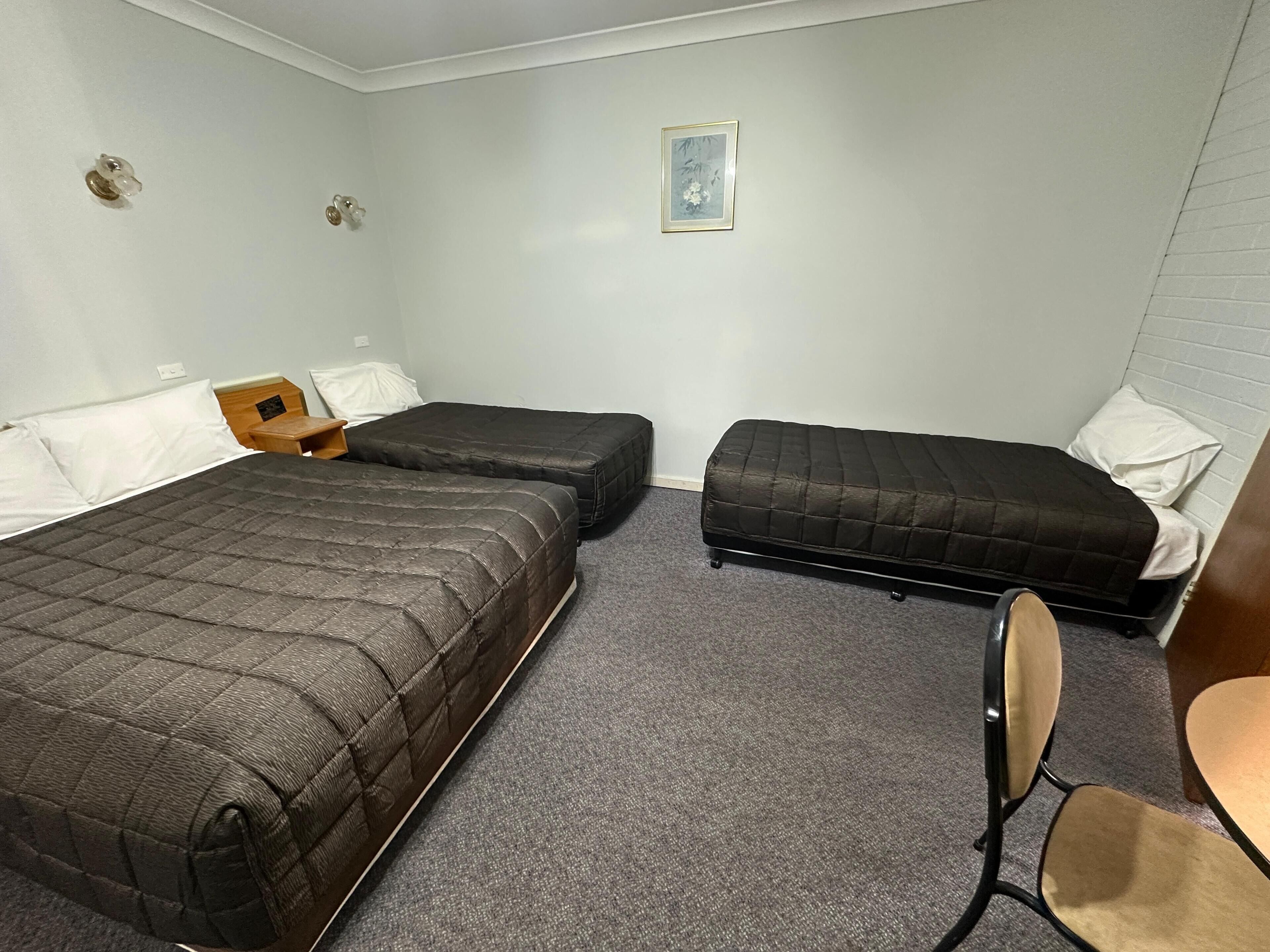 A room with two beds, a small table, and a chair.