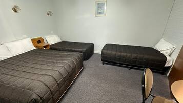 A room with two beds, a small table, and a chair.