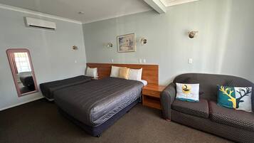 Quarto de hotel com uma cama grande, uma cadeira, uma mesa de cabeceira, um espelho e um quadro na parede.