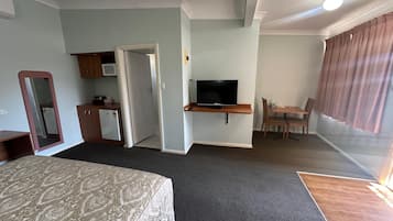 Une chambre d’hôtel comprenant un lit, un bureau avec une télévision, une petite kitchenette et un coin repas.