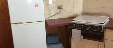 Une cuisine de taille réduite, avec un réfrigérateur blanc, un four à micro-ondes et une cuisinière.