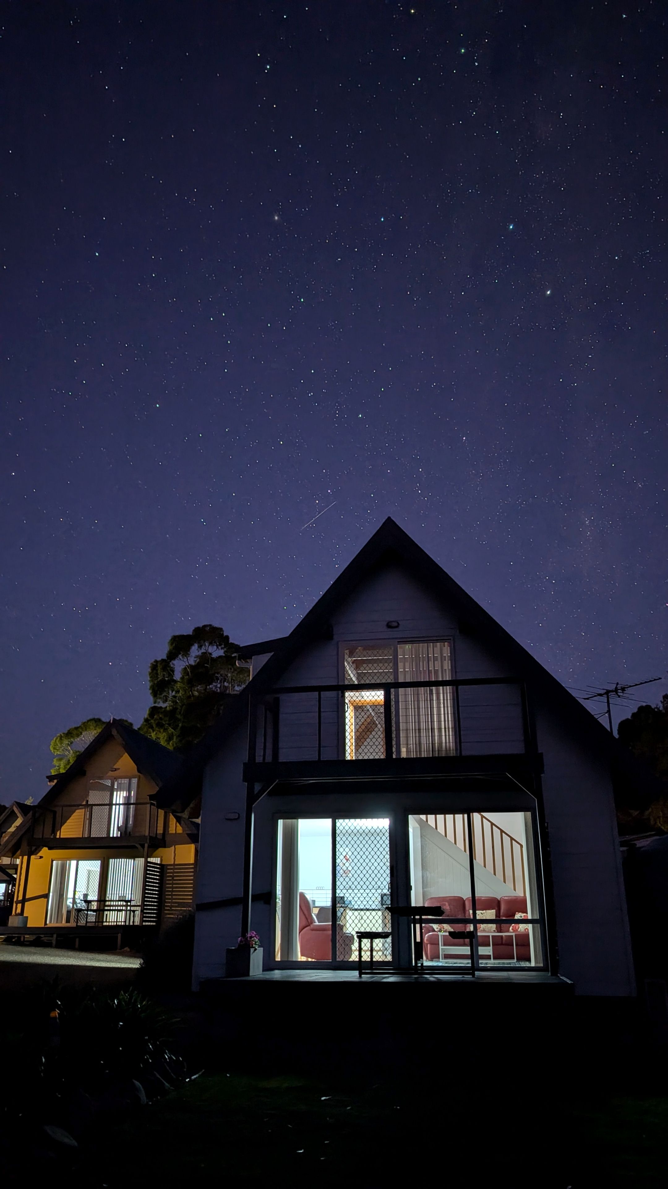 Een herenhuis met een balkon, grote ramen en een zichtbaar interieur met meubels.
