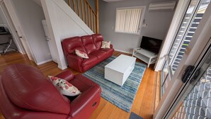 A living room with a red sofa, a white coffee table, and a TV on a stand. - Four Seasons Waterfront Villas (Taranna)