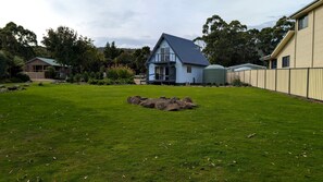 Una propiedad residencial con un césped bien cuidado, una gran roca ornamental y una casa con techo azul y balcón.