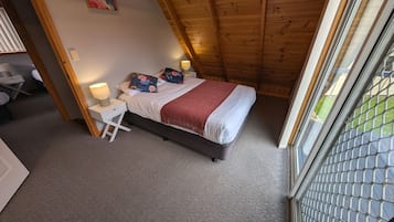 Een slaapkamer met een bed, bedlampen, een nachtkastje en uitzicht door een raam.