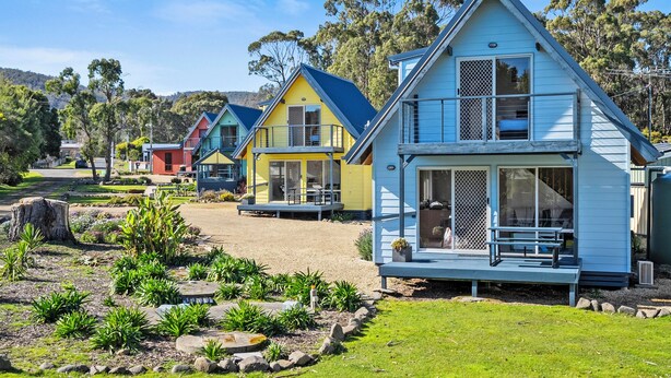 A row of colorful houses with a well-maintained garden in front. - Four Seasons Waterfront Villas (Taranna)