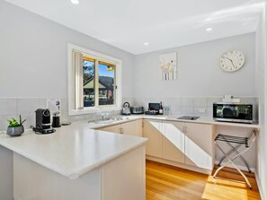 Una cocina moderna con una isla central, microondas, hervidor y pileta.