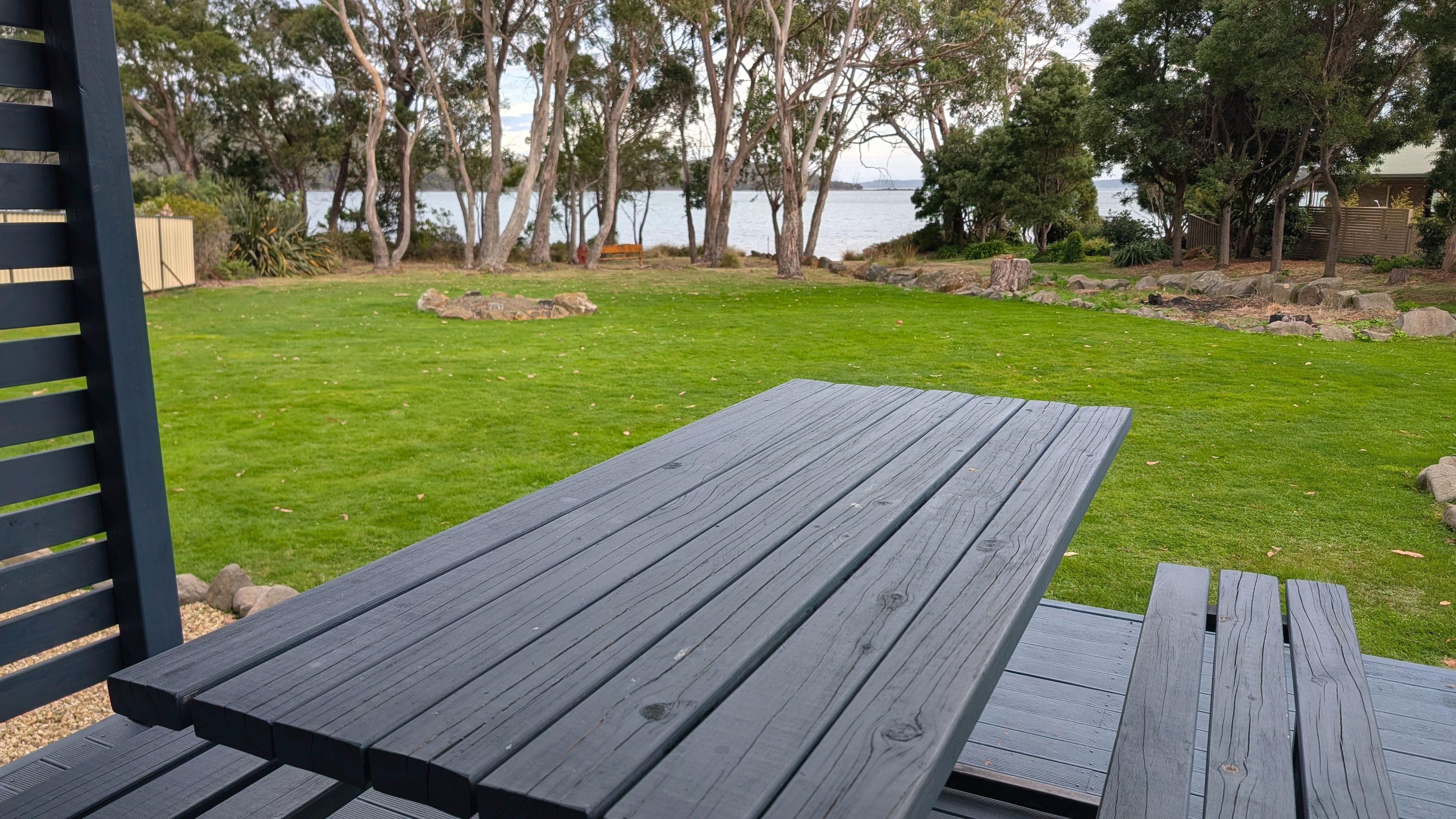 A wooden deck with a view of a grassy area and trees.