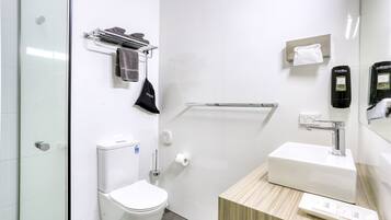 Moderni kylpyhuone, jossa on wc, pesuallas, pyyheteline ja käsienkuivaaja.