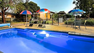 Una piscina al aire libre de temporada, sombrillas