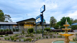 Un motel con un cartel que indica disponibilidad, una fuente y un jardín bien cuidado.