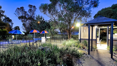 Una piscina al aire libre de temporada, sombrillas. Castle Creek Motel