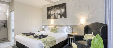Un dormitorio moderno con una cama grande, una mesita de noche, una silla y un cuadro en la pared.