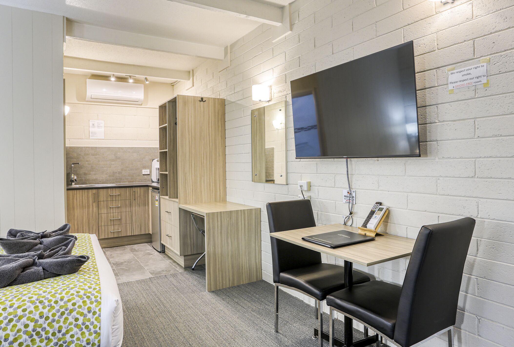 Une chambre d’hôtel comprenant un lit, un bureau avec une chaise, une télévision et une kitchenette.