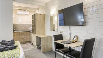 Une chambre d’hôtel comprenant un lit, un bureau avec une chaise, une télévision et une kitchenette.